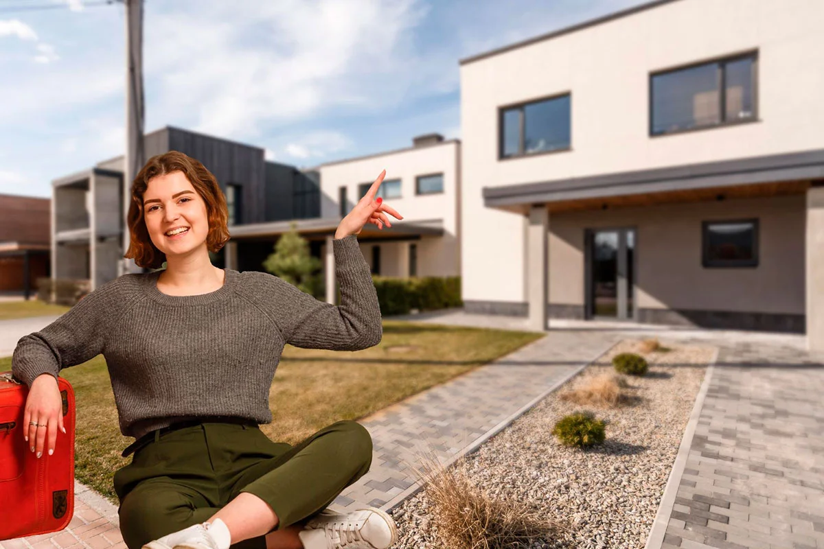 Mujer feliz mostrando una casa moderna como símbolo de inversión inmobiliaria exitosa con YADD Bienes Raíces